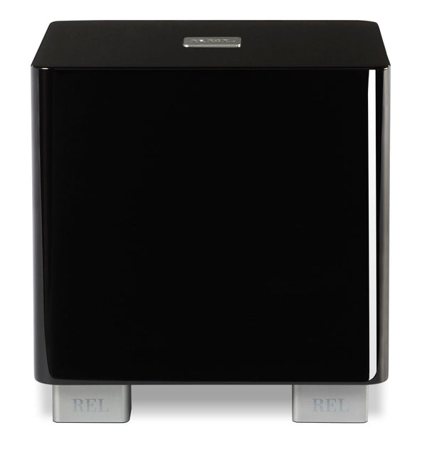 Subwoofer REL de alta fidelidad, acabado negro brillante con patas metálicas, ideal para sistemas de audio premium.